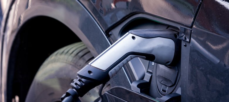 Elektromobilität Ein Ladekabel ist in den Ladeanschluss eines dunklen Elektroautos eingesteckt
