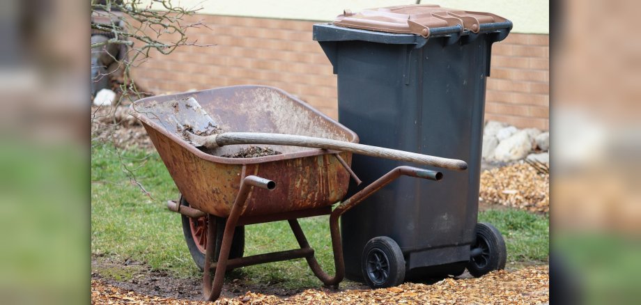 Braune Tonne mit Schubkarre