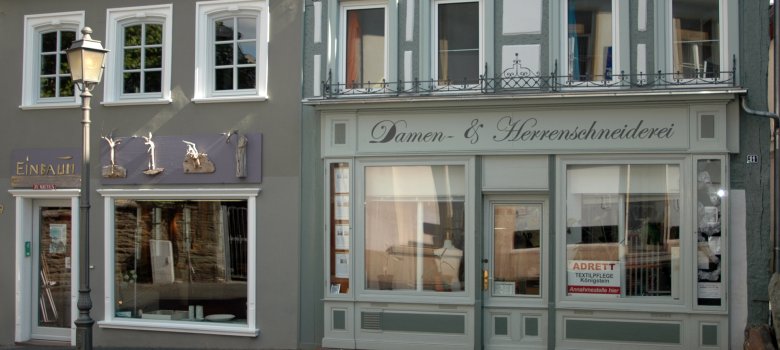 Grün Weißes Gebäude wo Damen und Herren Schneiderei draufsteht