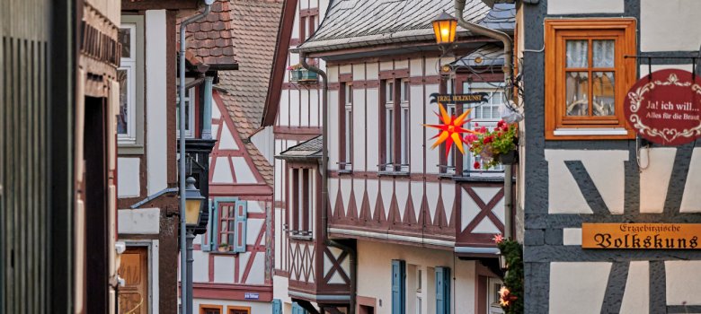 Eine malerische Gasse mit Kopfsteinpflaster, dekoriert mit Blumen, einer Nussknackerfigur und einem Schild für „Erzgebirgische Volkskunst“