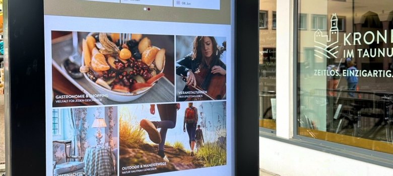 Ein digitaler Informationsbildschirm der Stadt Kronberg im Taunus im Außenbereich, der aktuelle Veranstaltungshinweise und touristische Angebote anzeigt.