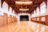 Perspektivische Ansicht der leeren Festhalle in Richtung der Bühne mit markanter Holzarchitektur