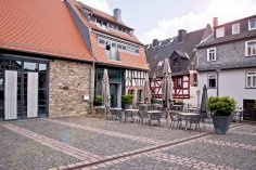 Die historische Zehntscheune in Kronberg im Taunus vom gepflasterten Zehntscheunen-Platz aus fotografiert, mit einer klassischen Straßenlaterne und dem Straßenschild im Vordergrund.