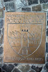 Eine rechteckige Bronzeplakette mit eingravierten Schriftzügen „KRONBERG IM TAUNUS“ und darunter „PORTO RECANATI“. Das Zentrum bildet ein großes Wappenschild mit einem Turm und mehreren Segelschiffen auf Wellen. Am unteren Rand steht die Gravur „GEGR. 1993 · KM: 1130