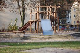 Klettergerüst mit großer Rutsche. Das Gerüst steht in einem großen Sandkasten