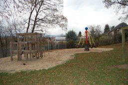 Ein Spielplatz mit einem Holz-Klettergerüst und einem auffälligen, bunten Karussell
