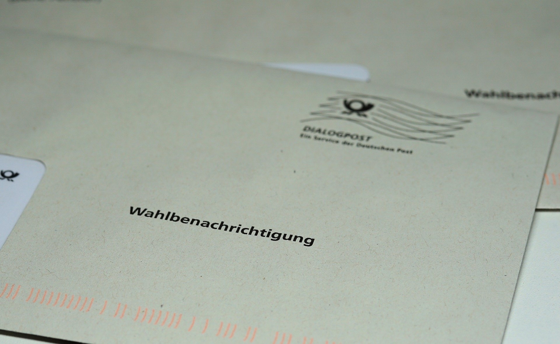 Ein Briefumschlag der Deutschen Post mit dem schwarzen Aufdruck „Wahlbenachrichtigung“ liegt im Fokus der Aufnahme. Im oberen rechten Bereich sind das Logo der „Dialogpost“ und ein stilisierter Poststempel zu sehen