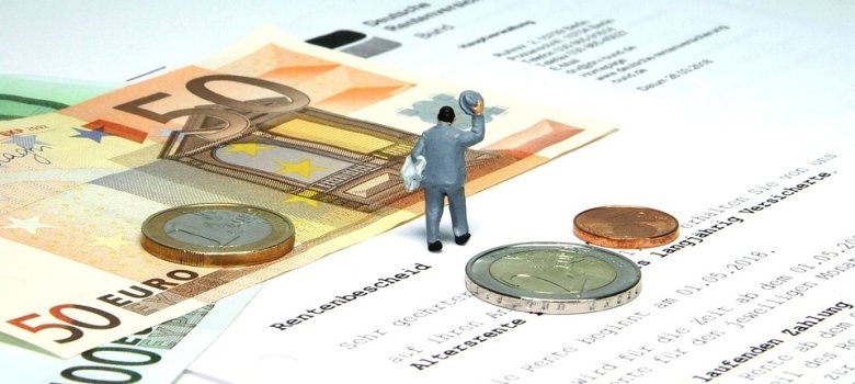 Nahaufnahme eines Schreibens der Deutschen Rentenversicherung mit dem Titel ‚Rentenbescheid‘. Darauf liegen Euro-Münzen und Geldscheine. Eine kleine Modellfigur eines Mannes blickt auf den Text