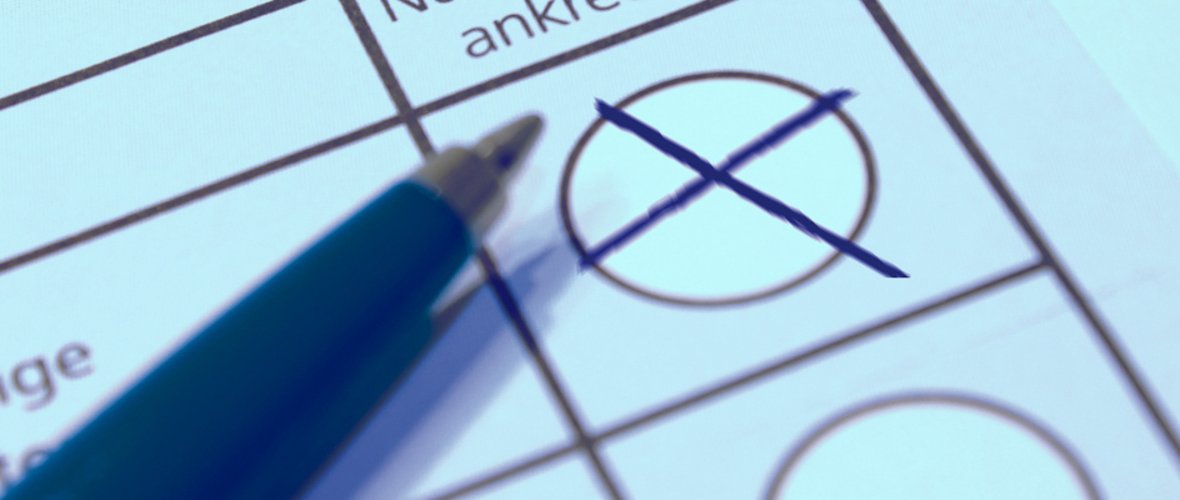 State parliament in Berlin Makroaufnahme eines offiziellen Wahlformulars; ein blauer Stift liegt daneben, nachdem ein schwarzes Kreuz in einem der runden Auswahlfelder platziert wurde. Im Hintergrund sind Textfragmente wie ‚führen‘ und ‚abhängige‘ erkennbar