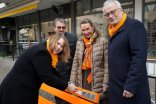 2)	Dr. Ulrike Zymolka befestigte gemeinsam mit Stadtverordnetenvorsteher Andreas Knoche, Zonta-Vertreterin Dr. Ulrike Bilstein und Bürgermeister Christoph König (v.li.) eine Plakette an der orangefarbenen Bank, auf der die Notfallnummer zu finden ist.