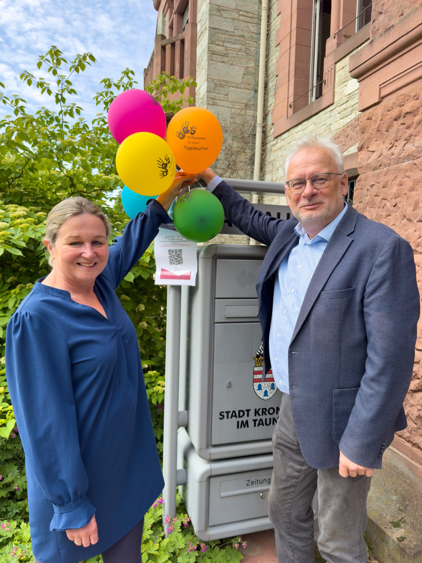 Mit bunten Luftballons wird in dieser Woche auch am Kronberger Rathaus auf die Arbeit der Kindertagespflege aufmerksam gemacht. Bürgermeister Christoph König (re.) und Fachbereichsleiterin Britta Markloff (li.) schätzen dieses Angebot als unverzichtbare Stütze der kommunalen Kinderbetreuung.