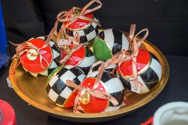 Schale mit Weihnachtskugeln Eine goldene Schale gefüllt mit auffälligen, handbemalten Weihnachtskugeln im Schachbrett- und Streifenmuster in den Farben Schwarz, Weiß, Rot und Grün, verziert mit Schleifen.