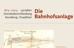 Eine beige Informationstafel mit der Überschrift „1874–2024 | 150 Jahre Eisenbahnverbindung Kronberg–Frankfurt“ links und dem großen, roten Titel „Die Bahnhofsanlage“ rechts daneben. Im unteren Teil ist ein historischer, handgezeichneter Gleisplan abgebildet. Der Plan trägt die Beschriftungen „Cronberger Eisenbahn“ und „Situation des Bahnhofes Cronberg a. T.“. Eingezeichnet sind unter anderem Gleisanlagen, „Personenhalle“, „Güterhalle“, „Ackerland“ und „Lagerplätze“. Rechts daneben steht ein roter Erklärungstext, beginnend mit „Situationsplan des ersten Kronberger Bahnhofs von 1874“